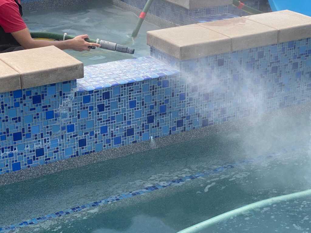 san diego pool tile cleaning technician during an active media blasting directly on the pool waterline